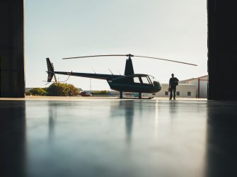 Silhouette of helicopter with a pilot walking in the airplane hangar after the flight.