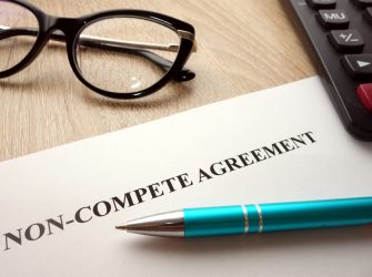 Photo of a desktop, pen, glasses and piece of paper with the title Non-Compete Agreement