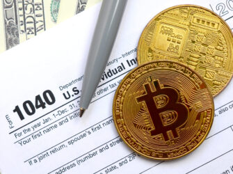 The pen, bitcoins and dollar bills is lies on the tax form 1040 U.S. Individual Income Tax Return. The time to pay taxes